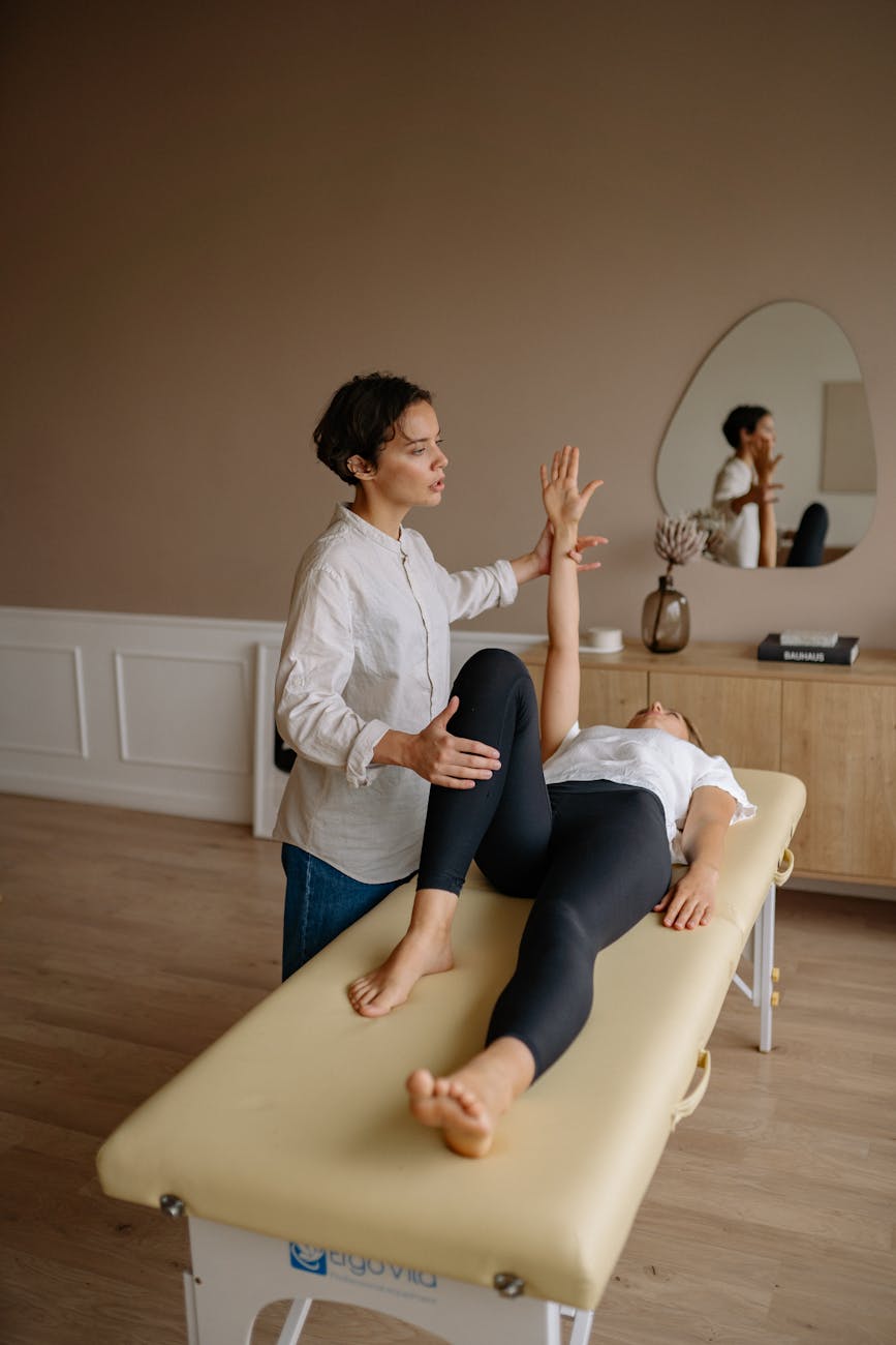 a person in white shirt and black pants lying on therapy bed